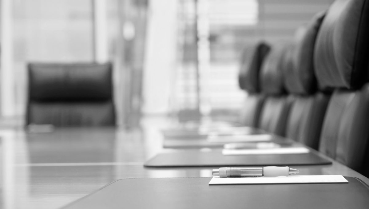 Modern boardroom table with digital data overlay, symbolising board-level focus on compliance, governance, and AI strategy in 2025.